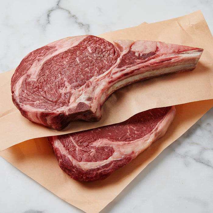 A can of Cat Person Beef Shreds in Broth is displayed on brown butcher paper atop a white marble surface.