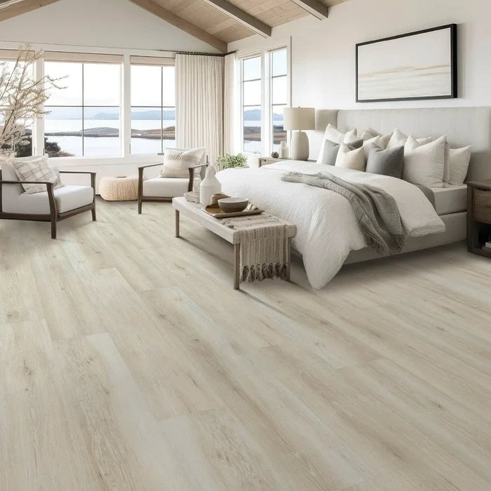 Modern bedroom with wooden flooring, bed, and seating area.