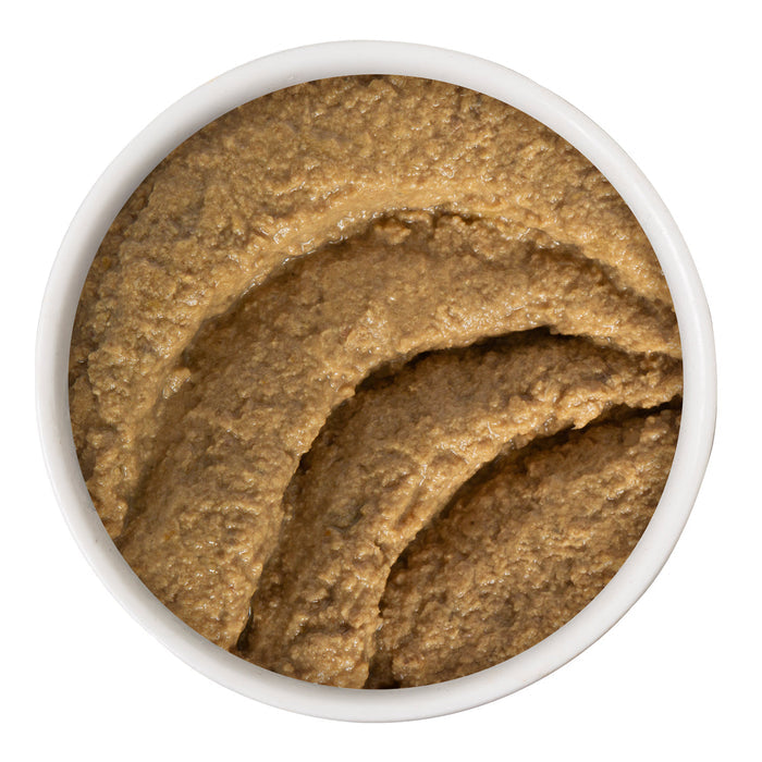 A white bowl contains smooth, brown Chicken & Tuna Tubular paste from BFF Best Feline Friend, viewed from above. The surface shows textured, curved lines where it has been stirred or spread evenly.