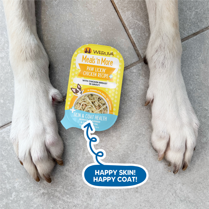 A Weruva Doggie Duo Variety Pack sits between two dog paws on a light floor, with the caption "Happy Skin! Happy Coat!" and an arrow pointing to the pack, emphasizing its skin and coat support benefits.
