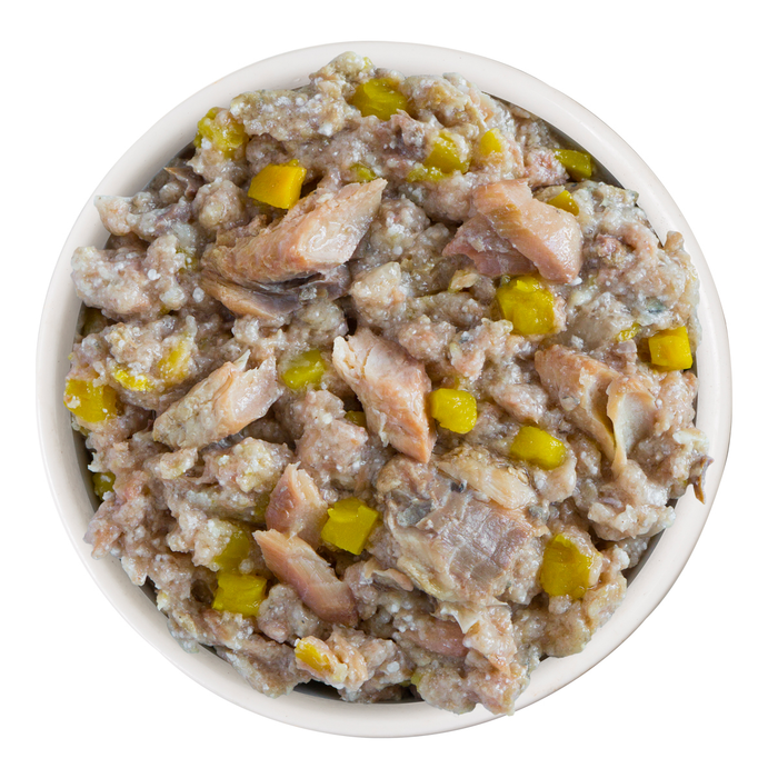 A bowl of Weruva Hot Dayam! dog food, featuring a chunky mix of grass-fed lamb, mackerel, and yellow vegetables, is shown from above on a white background.