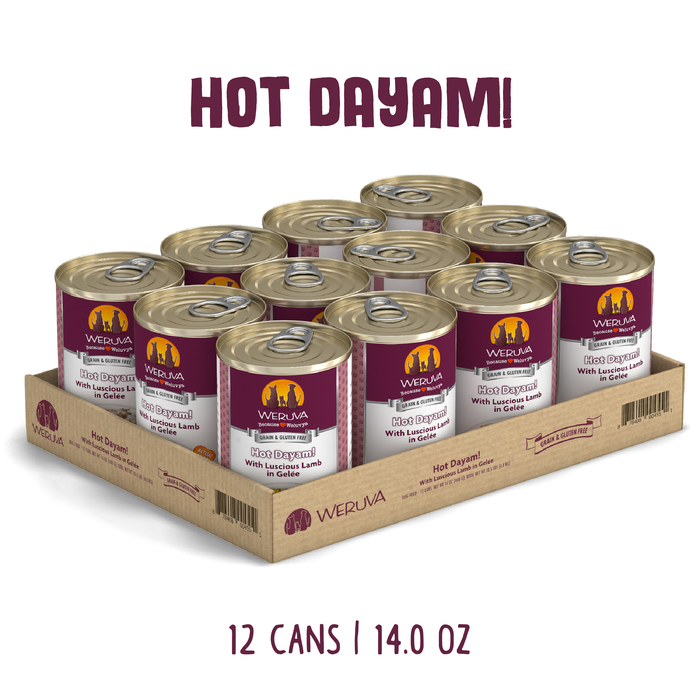 A Weruva Hot Dayam! cardboard tray holds 12 cans of grass-fed lamb & mackerel cat food in gelée, each can with maroon and beige labels. Above: "HOT DAYAM!" Below: "12 CANS | 14.0 OZ.