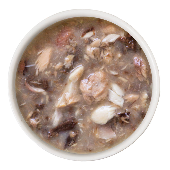 A white bowl filled with Cats in the Kitchen’s Mack, Jack and Sam shows chunky wild-caught salmon and mackerel pieces in a thick brown broth, viewed from above on a white background.