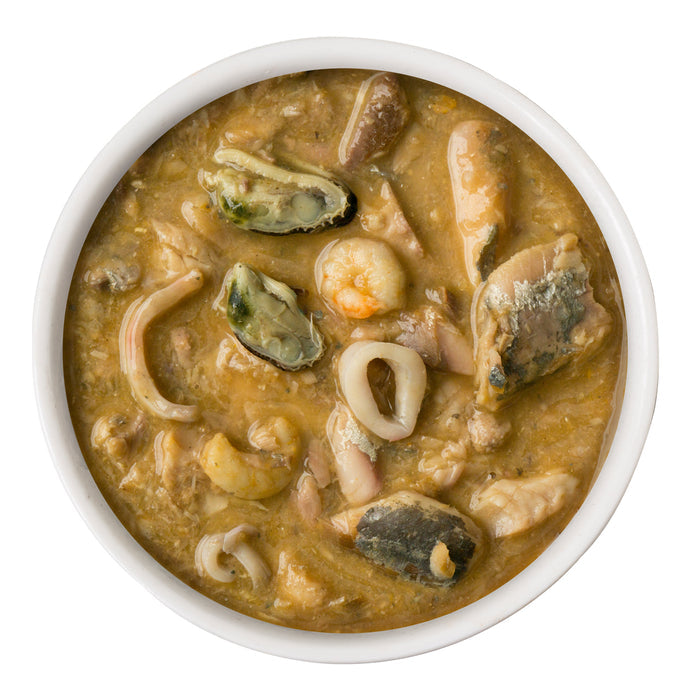 Weruva Marbella Paella features a thick, brown seafood stew with shrimp, mussels, squid rings, mackerel, and fish pieces, shown from above on a white background.