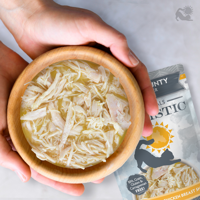 A person holds a wooden bowl of shredded chicken in broth. Behind them, a Soulistic Triple Harmony package with cat and dog silhouettes highlights high-protein, real meat nutrition for your pet.