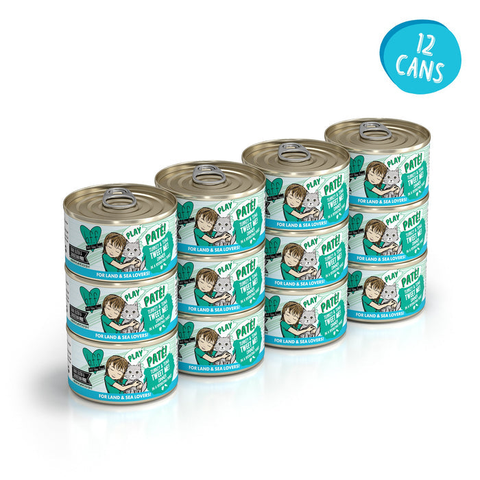 Twelve cans of BFF Best Feline Friend Turkey & Tuna Tweet Me! grain-free pet food are stacked in three rows. Teal and white labels show cartoon animals and include a 12-can blue circle, featuring turkey and wild-caught tuna varieties.